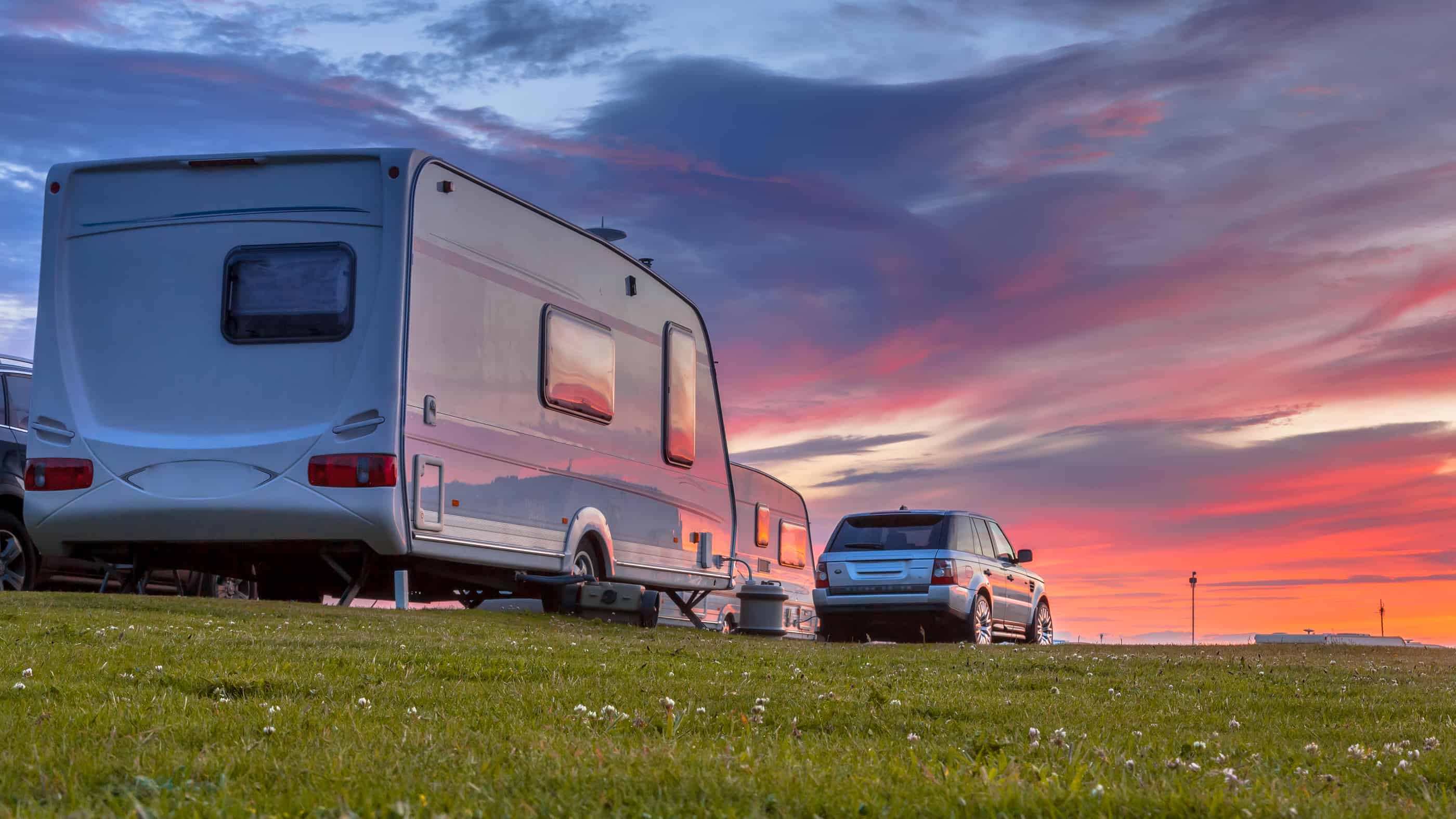 Camping Caravans And Cars Parked On A Grassy Campground Under Be